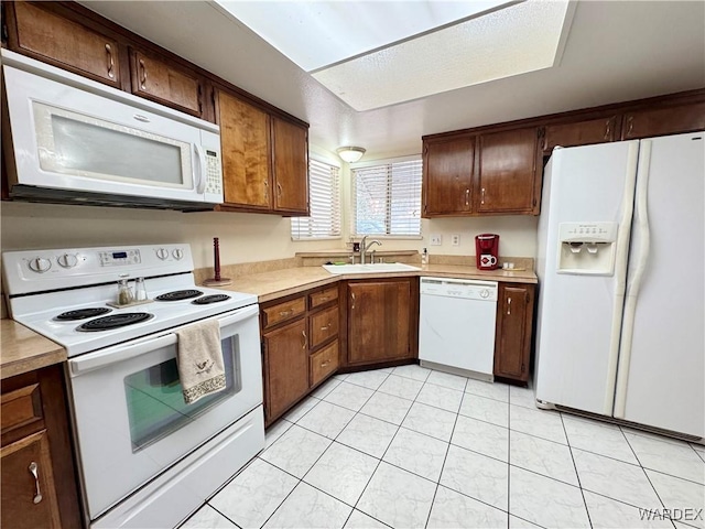 kitchen featuring light tile patterned flooring, white appliances, light countertops, and a sink