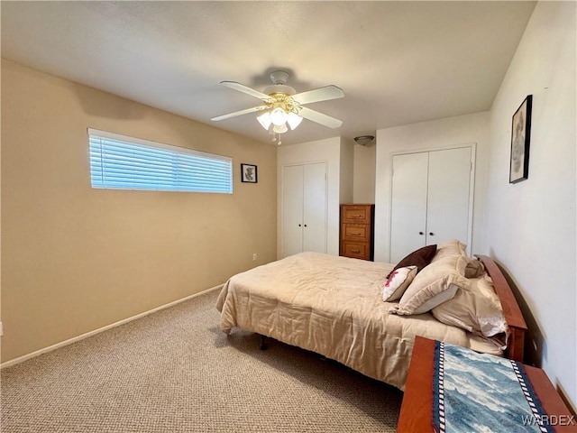 carpeted bedroom featuring baseboards, two closets, and a ceiling fan