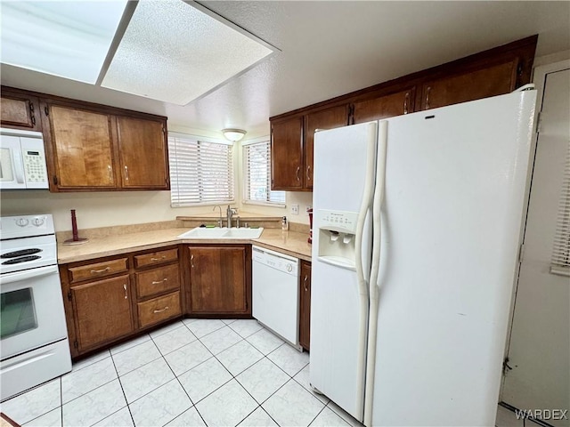 kitchen featuring a sink, white appliances, light tile patterned floors, and light countertops