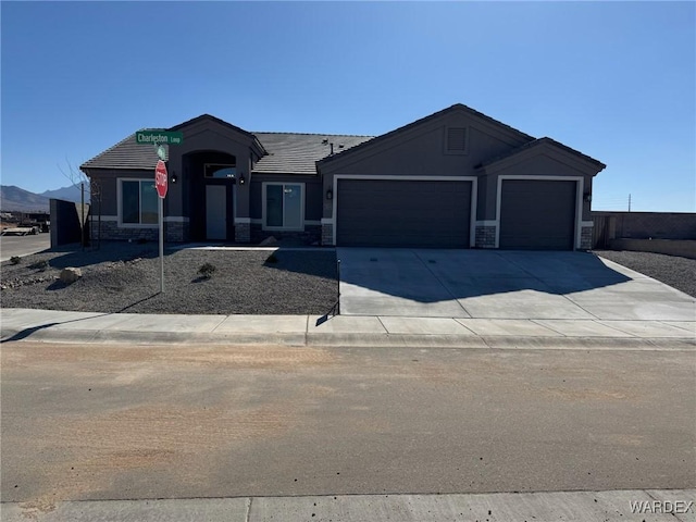 view of front of property with an attached garage, concrete driveway, stone siding, a tiled roof, and stucco siding