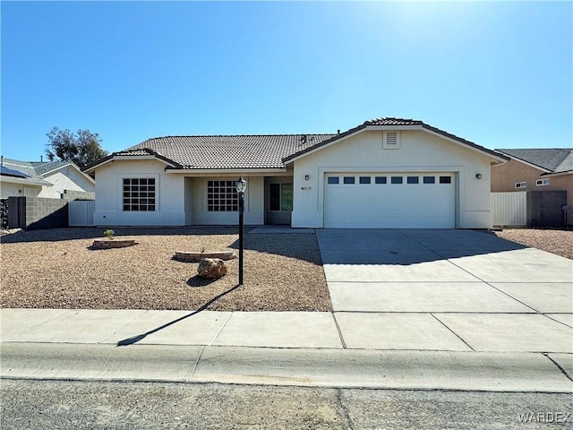 ranch-style home with a garage, fence, stucco siding, a tiled roof, and driveway