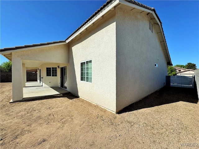 back of house featuring a patio area, stucco siding, and a tile roof