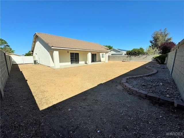 rear view of house with a tiled roof, a fenced backyard, and stucco siding