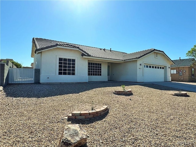 single story home featuring a tiled roof, a garage, fence, concrete driveway, and stucco siding