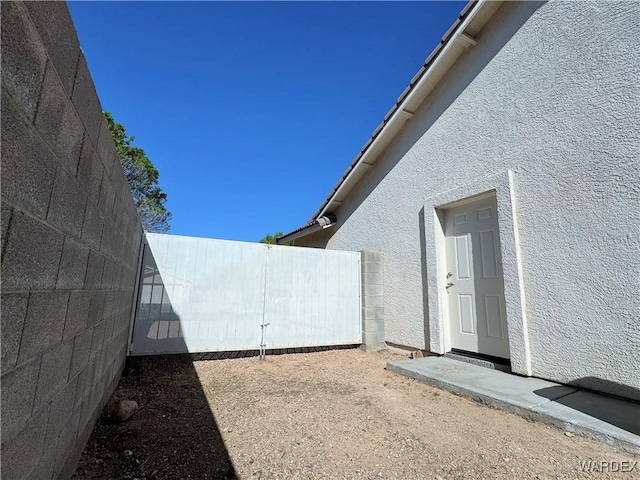 view of side of home with fence and stucco siding