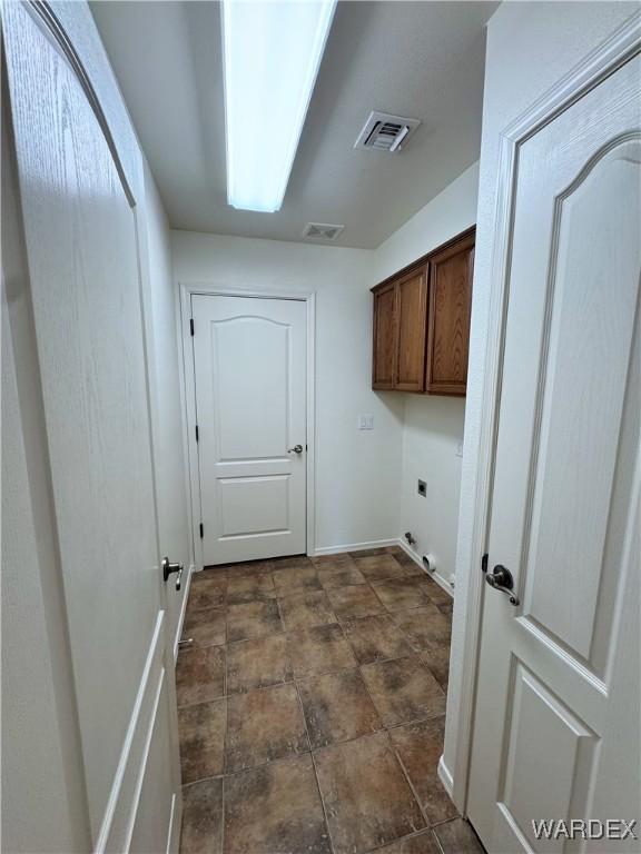 laundry area with electric dryer hookup, cabinet space, and visible vents