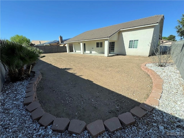 rear view of property featuring a tiled roof, a patio, a fenced backyard, and stucco siding