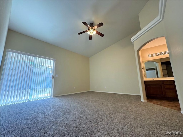 unfurnished bedroom with baseboards, arched walkways, carpet, and lofted ceiling