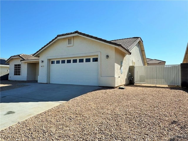 view of front of property featuring driveway, a tile roof, a garage, fence, and stucco siding
