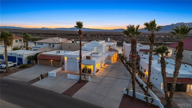 view of front of property with driveway, an attached garage, a residential view, and a mountain view