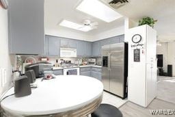 kitchen featuring white microwave, gray cabinets, light countertops, and stainless steel fridge with ice dispenser