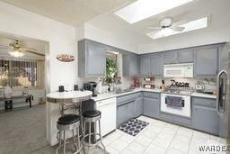 kitchen featuring light countertops, white microwave, a ceiling fan, and gray cabinetry