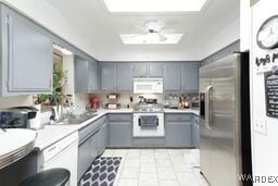 kitchen featuring stainless steel fridge, gray cabinets, light countertops, and white microwave