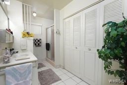 bathroom featuring a stall shower, tile patterned flooring, a closet, and a sink