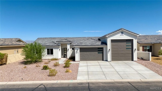 view of front of property with concrete driveway, an attached garage, fence, and stucco siding