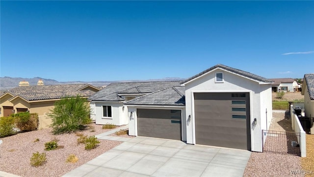 view of front facade featuring an attached garage, a mountain view, fence, concrete driveway, and stucco siding