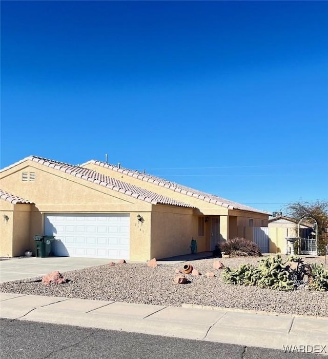 single story home with driveway, a tile roof, an attached garage, and stucco siding