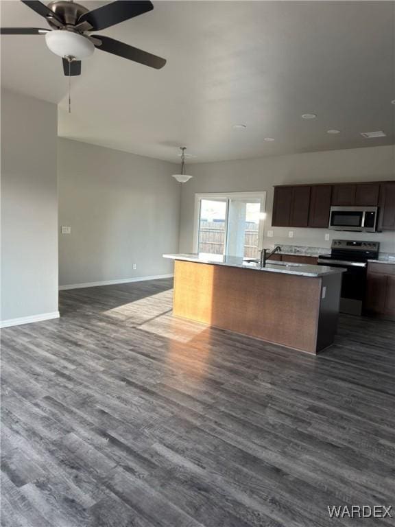 kitchen featuring appliances with stainless steel finishes, open floor plan, a kitchen island with sink, and dark wood-style floors