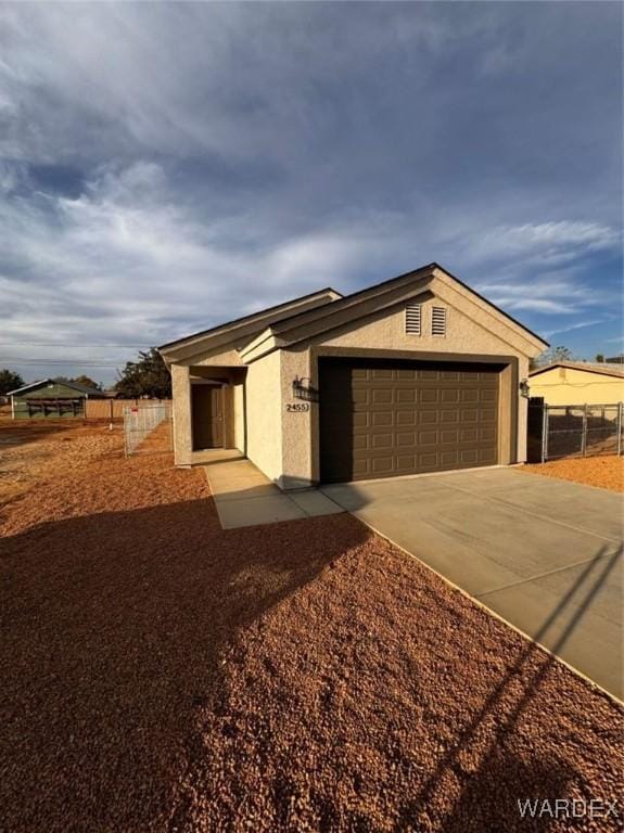 ranch-style home featuring concrete driveway, an attached garage, fence, and stucco siding