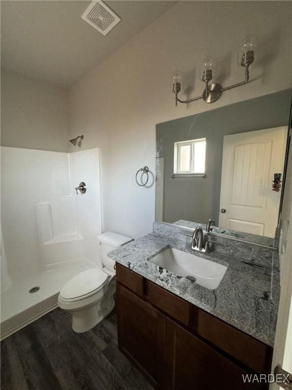 full bath with visible vents, toilet, a shower stall, vanity, and wood finished floors