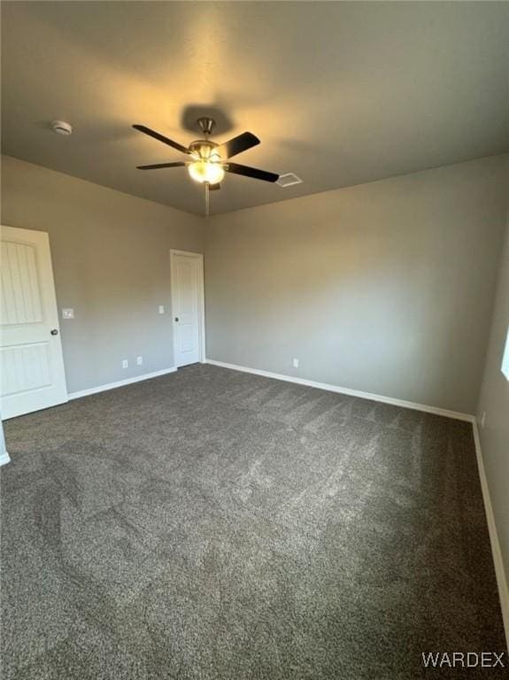 unfurnished room featuring a ceiling fan, dark colored carpet, and baseboards