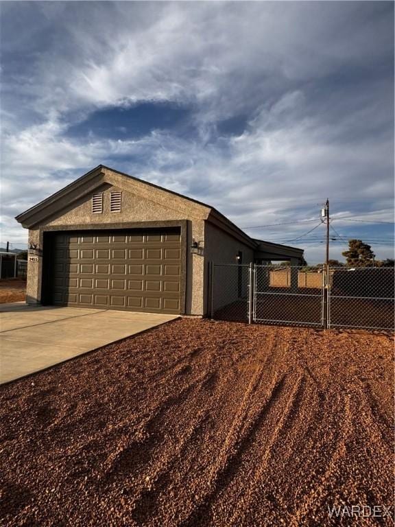 view of side of home with an outbuilding, a garage, fence, concrete driveway, and stucco siding