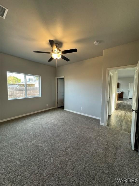 unfurnished bedroom featuring ceiling fan, dark carpet, visible vents, and baseboards