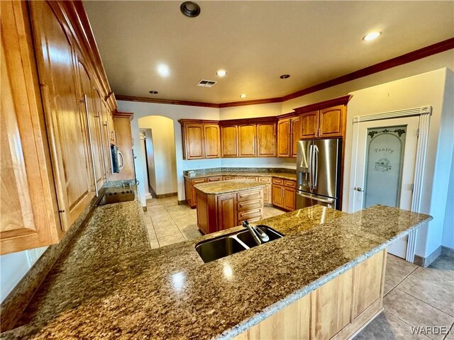 kitchen featuring arched walkways, visible vents, a center island, stainless steel appliances, and a sink