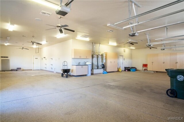 garage with strapped water heater, visible vents, and a garage door opener