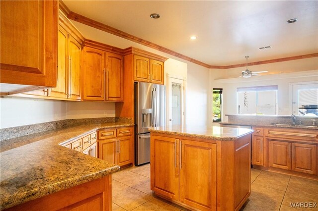 kitchen featuring visible vents, brown cabinetry, stainless steel fridge with ice dispenser, a center island, and a sink