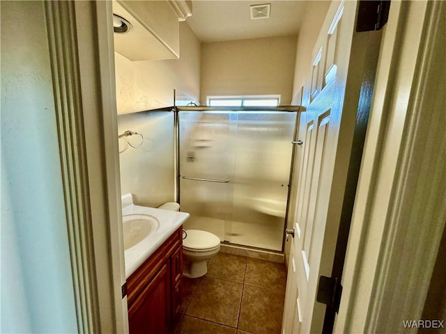 bathroom with toilet, vanity, visible vents, tile patterned floors, and a stall shower