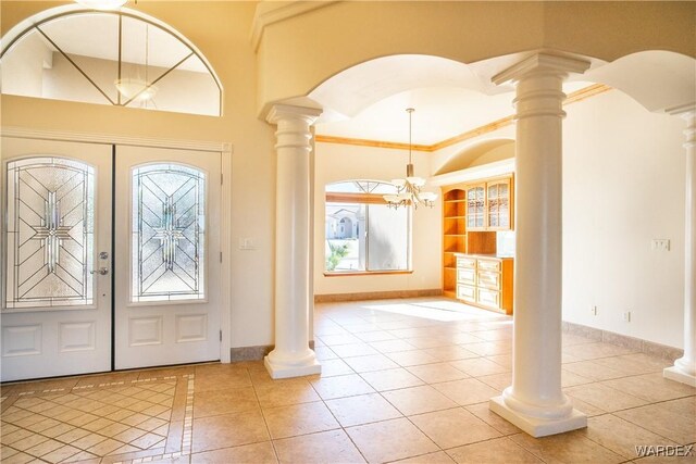 foyer featuring light tile patterned floors, decorative columns, arched walkways, ornamental molding, and french doors