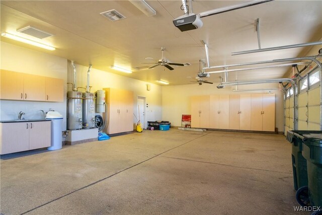 garage featuring a garage door opener, gas water heater, visible vents, and a sink