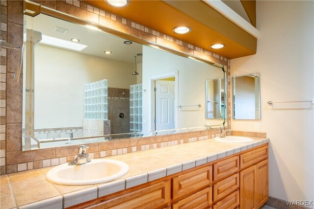 bathroom featuring walk in shower, a sink, a bath, and double vanity