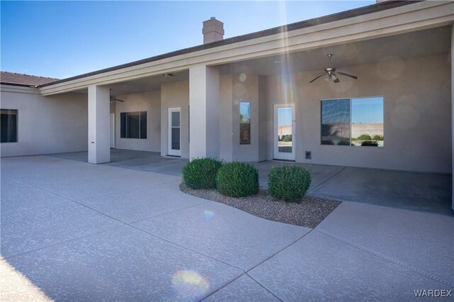 exterior space with a patio area, ceiling fan, a chimney, and stucco siding