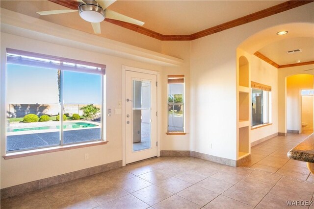 entryway featuring arched walkways, visible vents, ornamental molding, a ceiling fan, and baseboards