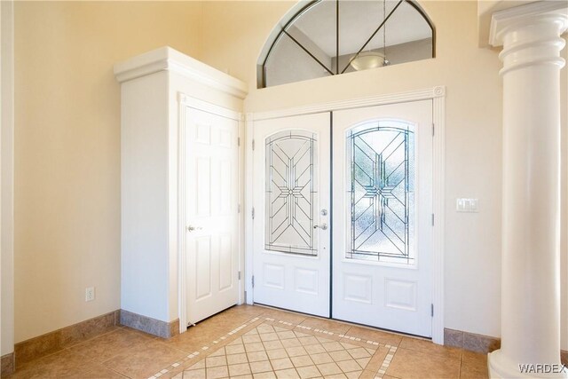 foyer featuring light tile patterned floors, baseboards, ornate columns, and french doors