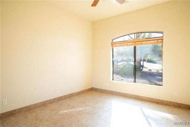 empty room featuring ceiling fan, light tile patterned floors, and baseboards