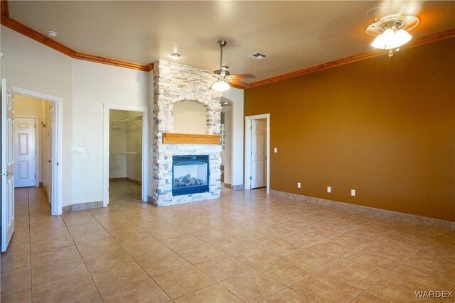 unfurnished living room featuring baseboards, visible vents, a ceiling fan, crown molding, and a stone fireplace