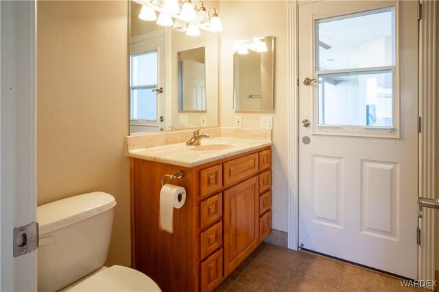 bathroom featuring toilet, vanity, a notable chandelier, and tile patterned floors