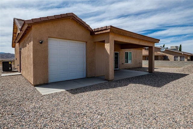 view of front of property with stucco siding, fence, a garage, central AC unit, and a tile roof