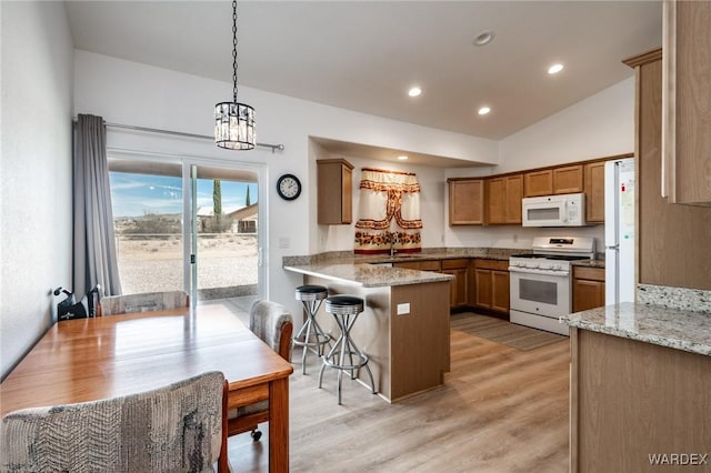kitchen featuring brown cabinets, light wood-style floors, a peninsula, white appliances, and hanging light fixtures