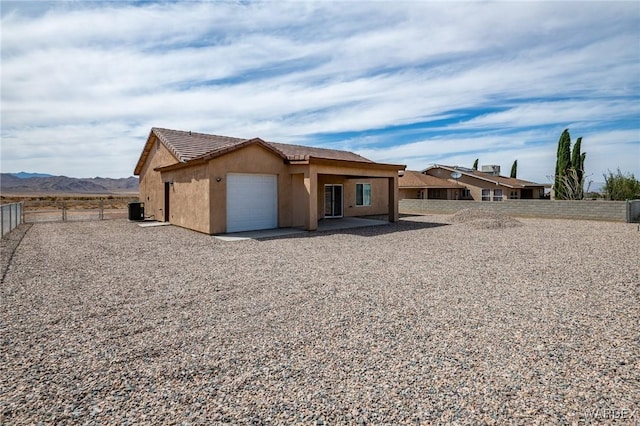 view of front of house featuring a tiled roof, stucco siding, a mountain view, an attached garage, and fence