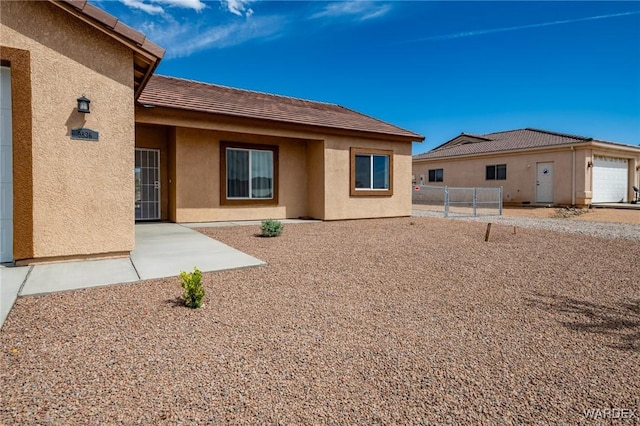 exterior space with fence, stucco siding, and a tiled roof