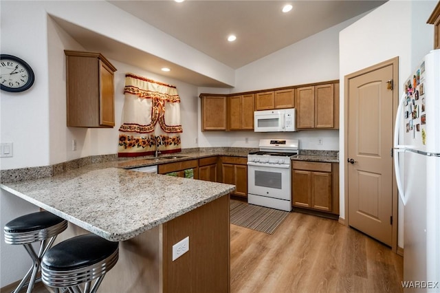 kitchen with white appliances, brown cabinets, a sink, a peninsula, and lofted ceiling