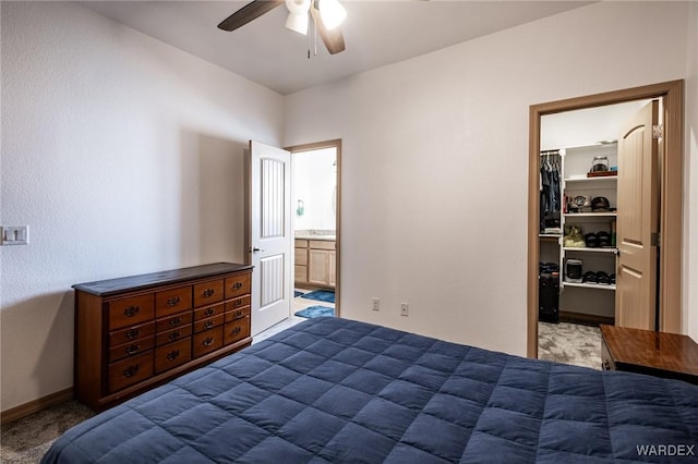 bedroom with baseboards, connected bathroom, a closet, dark colored carpet, and a walk in closet