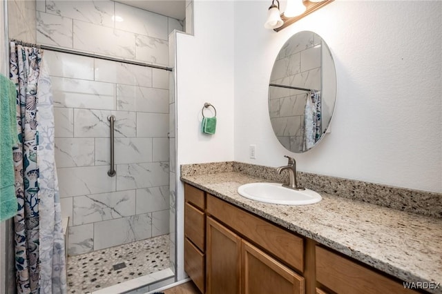 bathroom with tiled shower and vanity