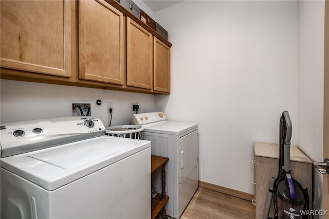 laundry area with baseboards, cabinet space, washing machine and clothes dryer, and light wood-style floors