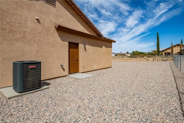 exterior space featuring cooling unit, stucco siding, and fence
