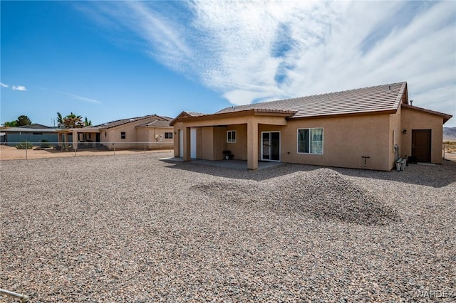 back of property featuring a patio area, stucco siding, a tiled roof, and fence
